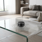 Black portable speaker on a glass coffee table in a modern living room.