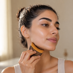 Woman using a facial brush in front of a mirror